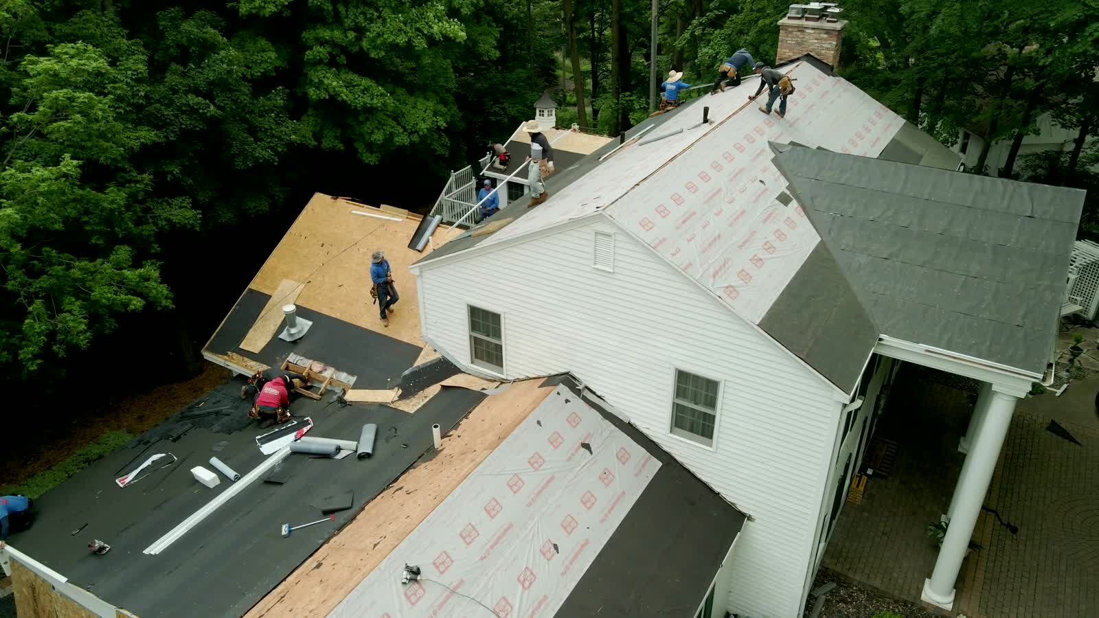 Roof replacement crew working on a residential roof during an educational storm recovery guide.